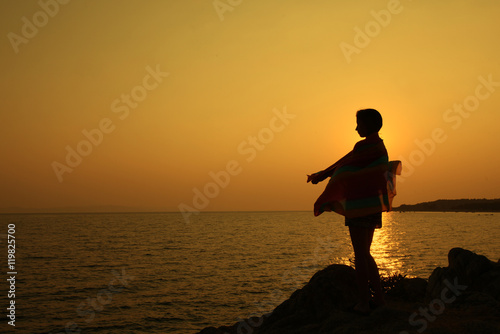 Girl is standing on seaside during beautiful sunset