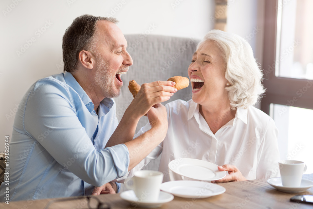 Cheerful senior couple eating croissant Cheerful senior couple eating croissant