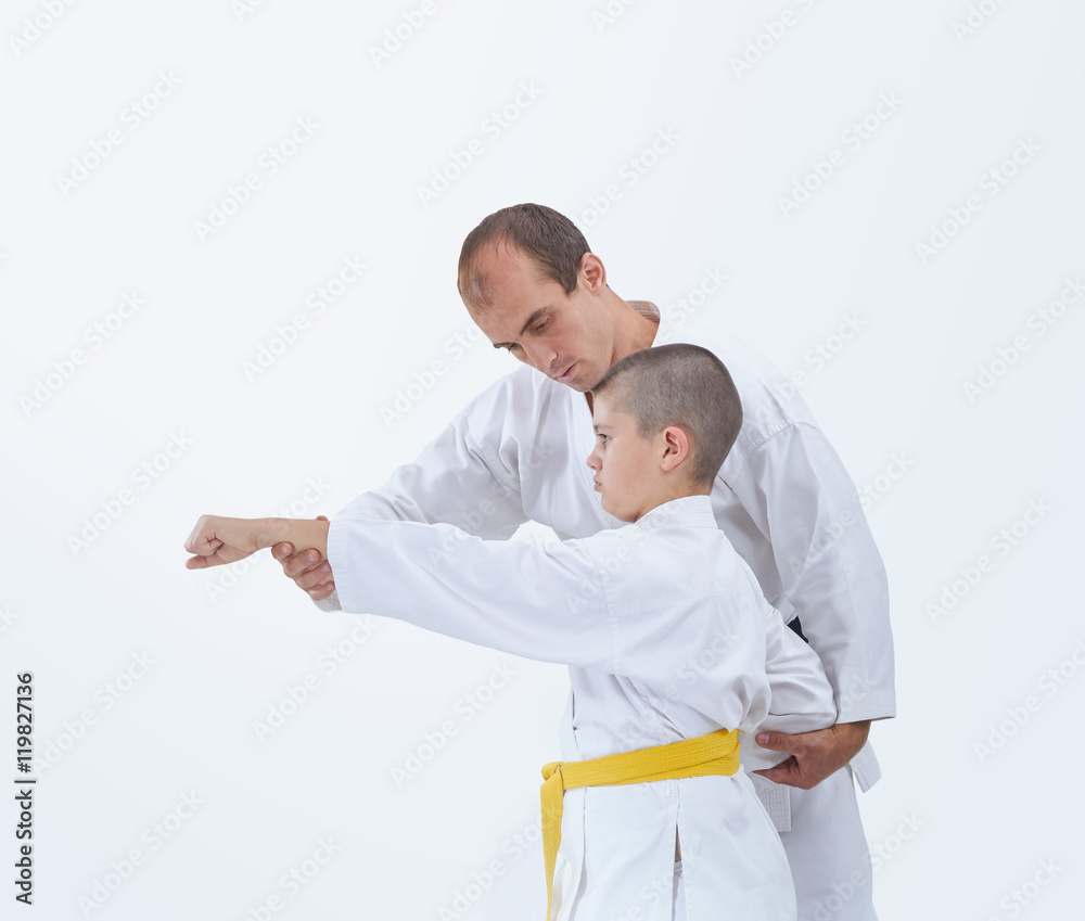 On a white background coach teaches the athlete to beat a punch arm