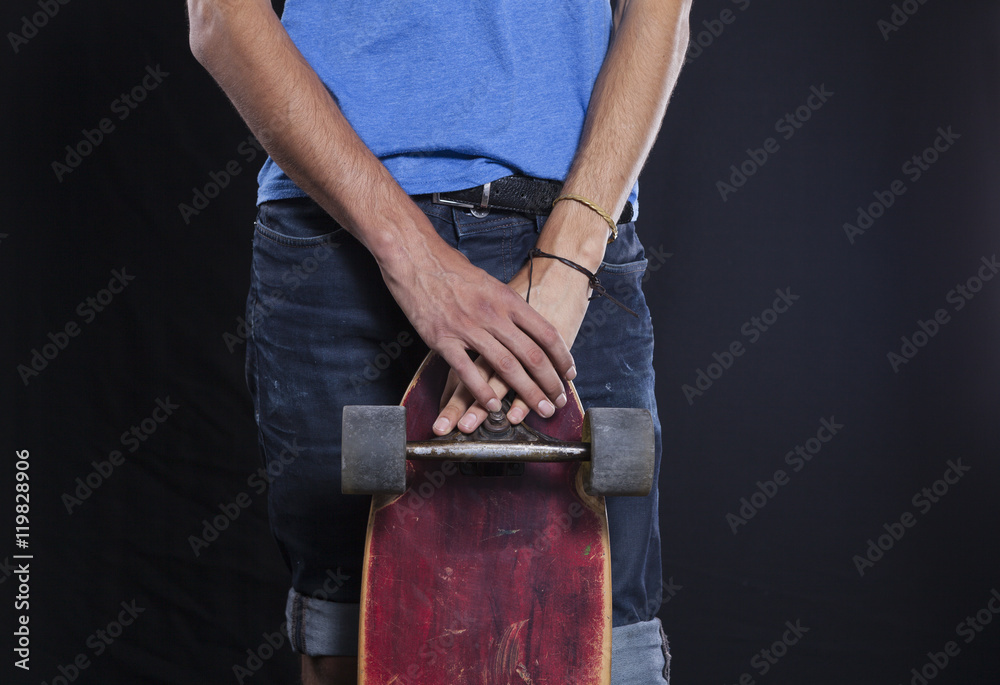 Detalle de una patineta y un joven portándola Detalle de una patineta y un joven portándola