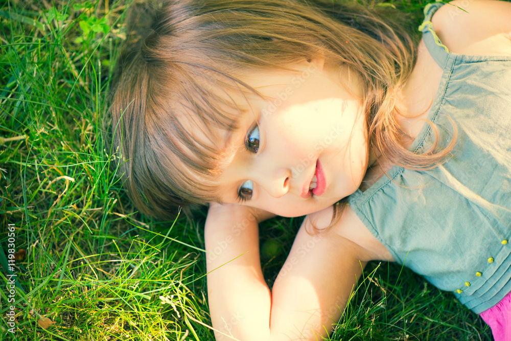 Cute smiling little girl lying on green grass Cute smiling little girl lying on green grass