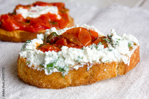 Bruschetta with ricotta cheese and tomato sauce on fabric background in a form of heart
