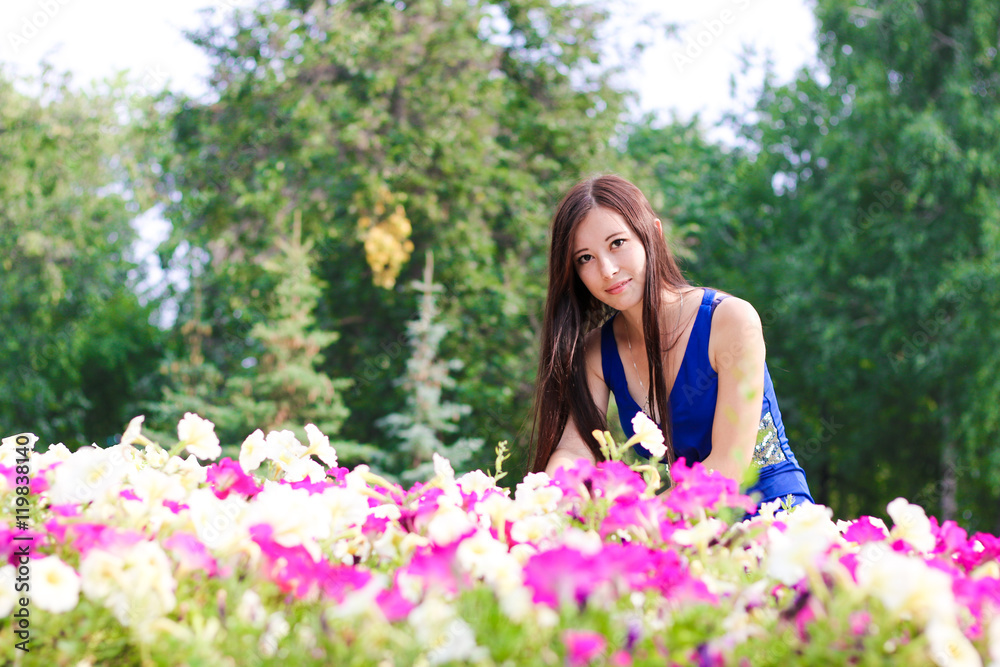 Young woman, student, sits near the flowers in the Park Young woman, student, sits near the flowers in the Park
