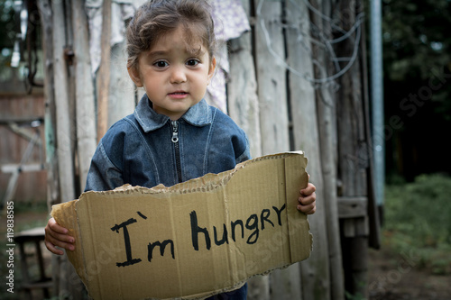 Little girl holding a sheet of cardboard. On the cardboard label 