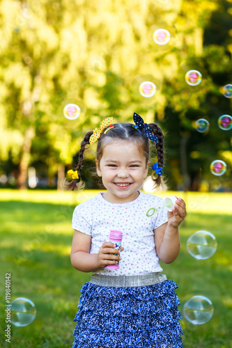 little girl blowing bubbles in the park