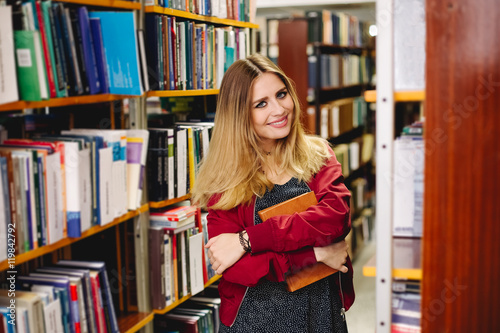 Smiling girl with a book in university library. Education concept