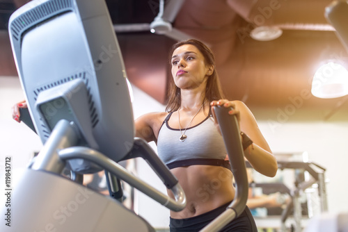Fit woman doing exercise on a elliptical trainer.