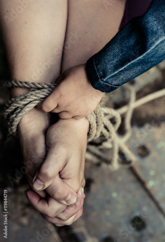 Thick rope ties the hands of women. Child's hand holding a rope. 