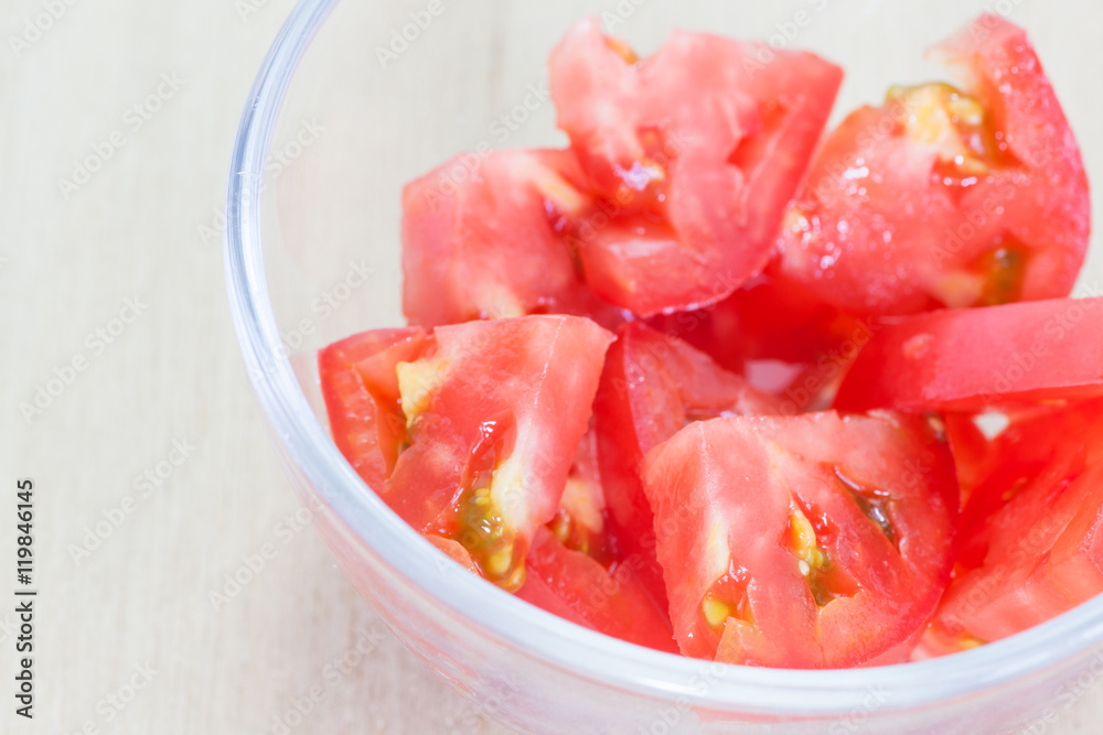 Fresh red tomato slice in glass bowl on wood table background Fresh red tomato slice in glass bowl on wood table background