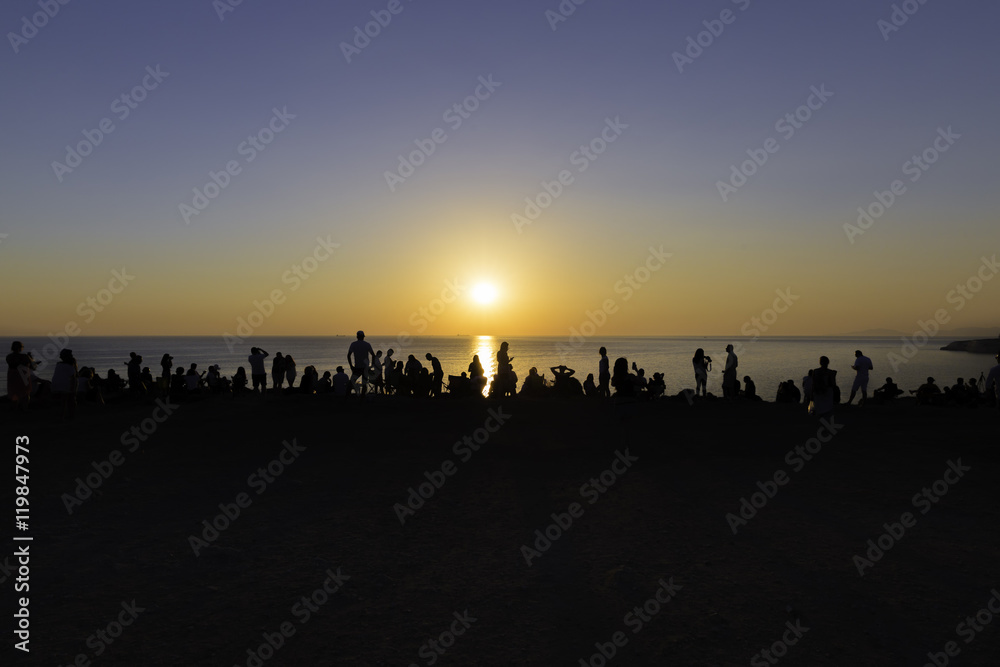 People silhouette watching sunset on the edge of the cliff near Polente lighthouse at Bozcaada island