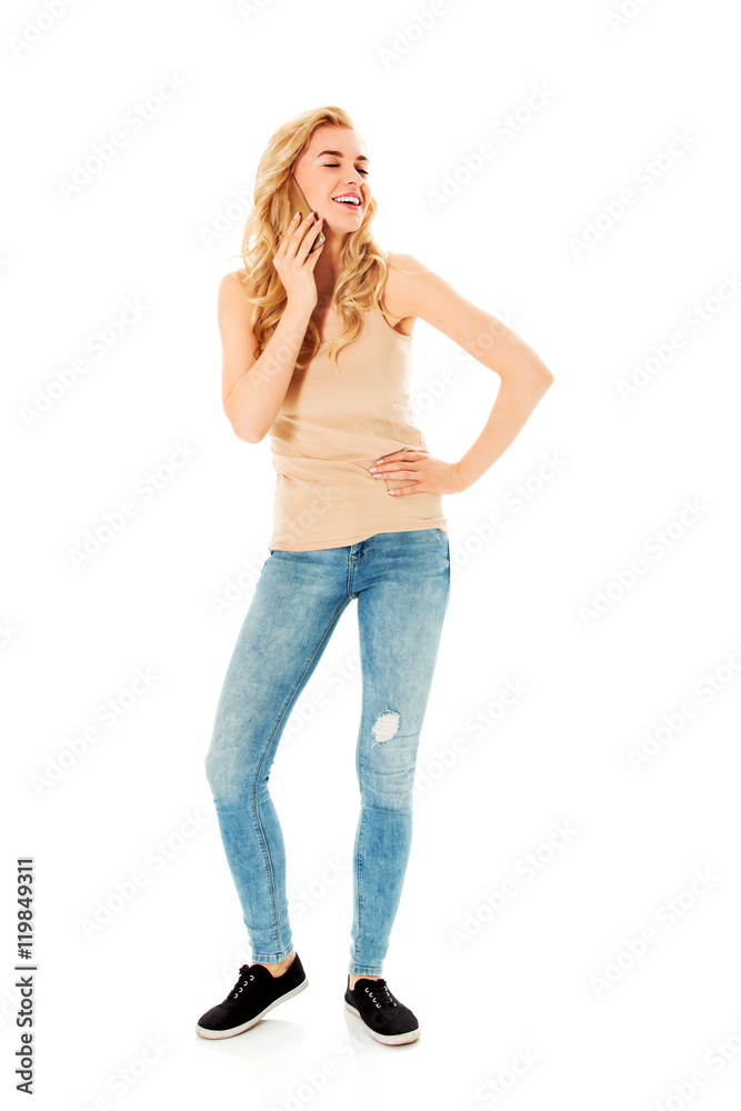 Obraz premium Young happy blonde woman talking through a smartphone