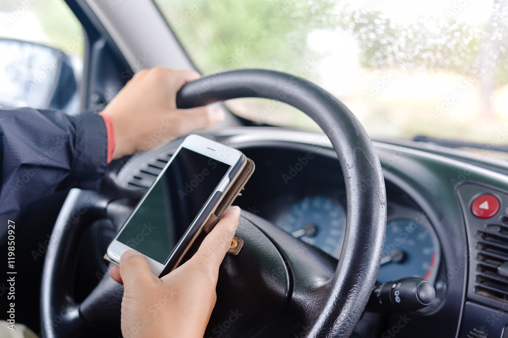 Closeup on hand holding phone with blank display, car wheel background