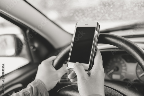 Closeup on hand holding smartphone in a car interior background