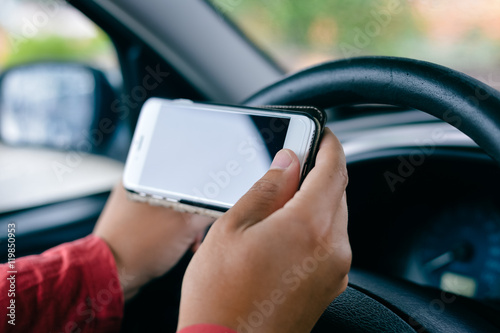 Car driver using smart phone, closeup on hand, mockup screen background