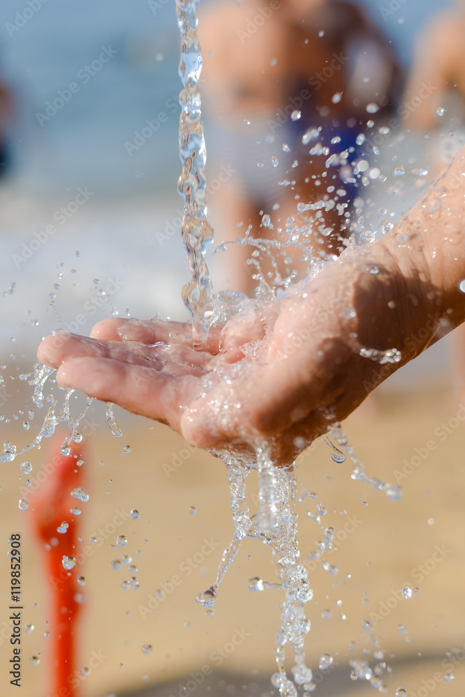 Fototapeta premium Close up of human hand catching water, ocean beach outdoors background