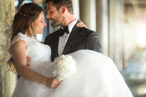 Romantic beautiful married wedding couple groom carries bride in his arms embrace
