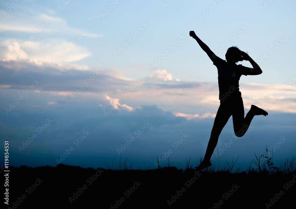 Silhouette of Happy woman jumping in green field against blue sk