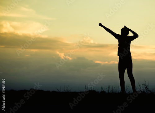 Silhouette of happy young woman jumping against sunset in the mo
