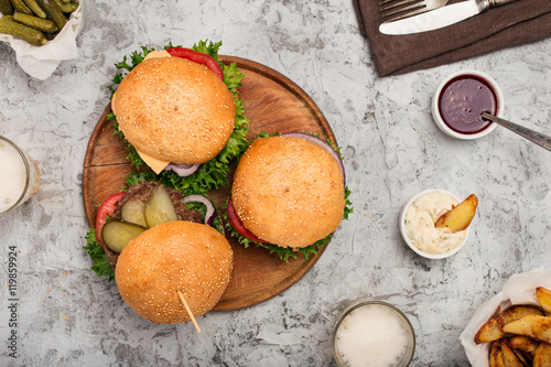 Burgers grilled on wooden round board with light beer photo