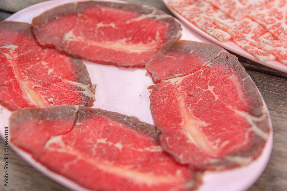 Pieces of raw fresh paper-thin sliced beef for grill to make Japanese yakiniku on plate.