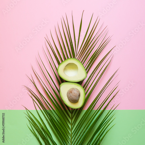 Ripe Avocado on palm leaf on a colored background. Minimal concept
