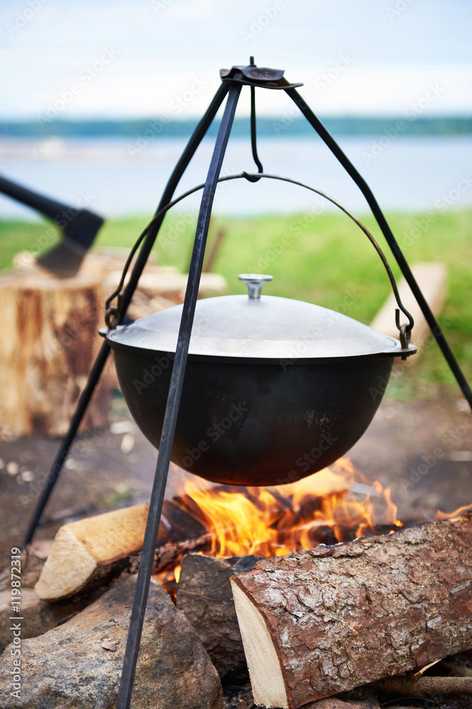 Hiking landscape with bonfire, pot and ax Hiking landscape with bonfire, pot and ax
