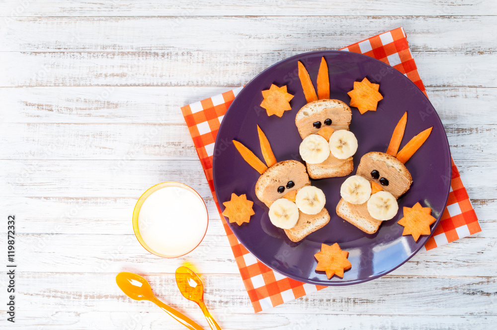 Children's breakfast with sandwiches and milk. Funny rabbit face sandwiches with peanut butter, banana and carrots