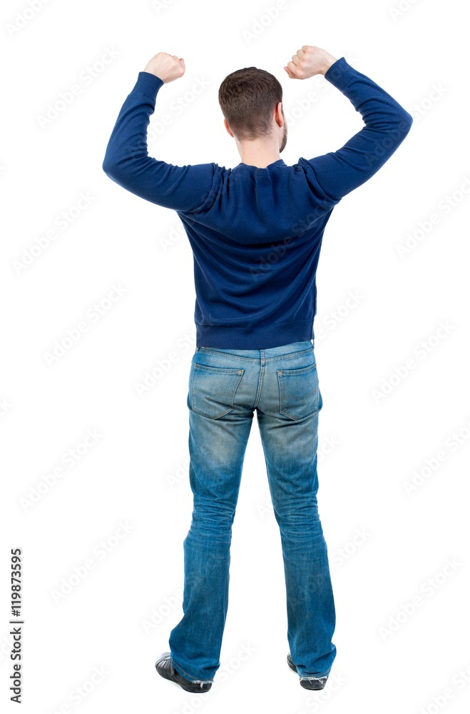 Back view of man. Raised his fist up in victory sign. bearded man in blue pullover happily waving their fists. Back view of man. Raised his fist up in victory sign. bearded man in blue pullover happily waving their fists.