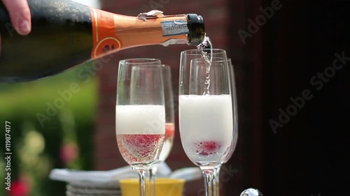 Close up shot of someone pouring champagne to glasses in the summer outdoors, slow motion