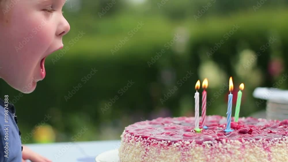 Close up of a young boy blowing out birthday candles, slow motion