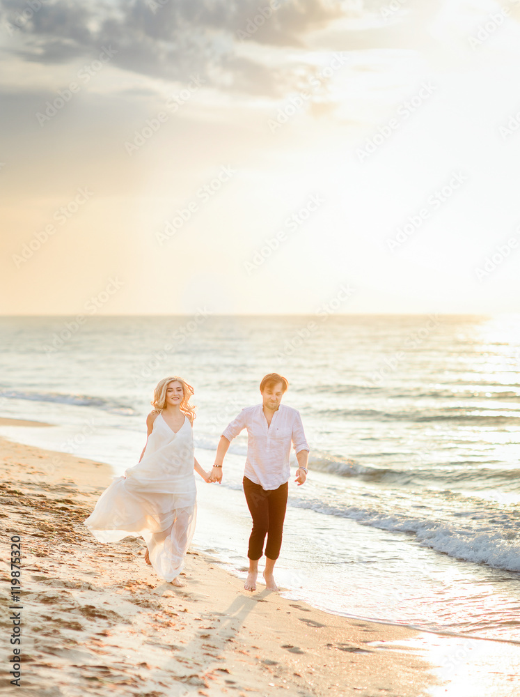Beautiful stylish couple walking on the beach Beautiful stylish couple walking on the beach