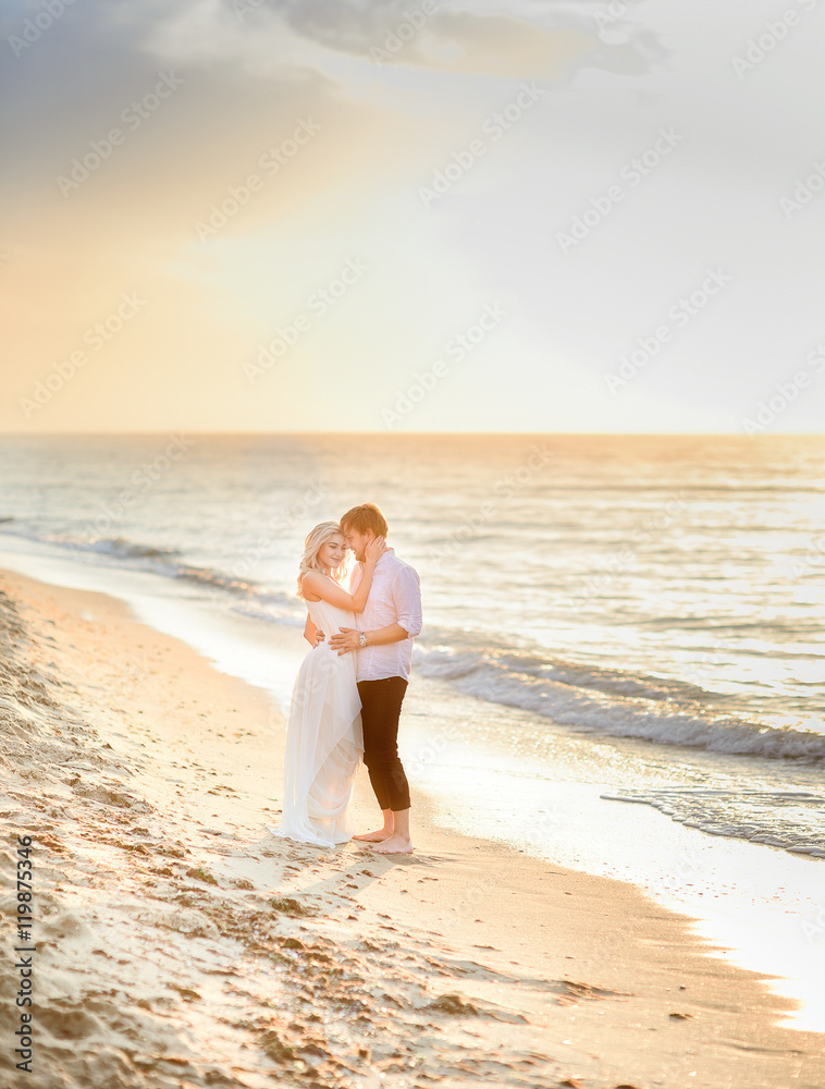 Beautiful stylish couple posing in sunlight on the beach Beautiful stylish couple posing in sunlight on the beach