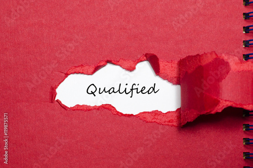 The word qualified appearing behind torn paper photo