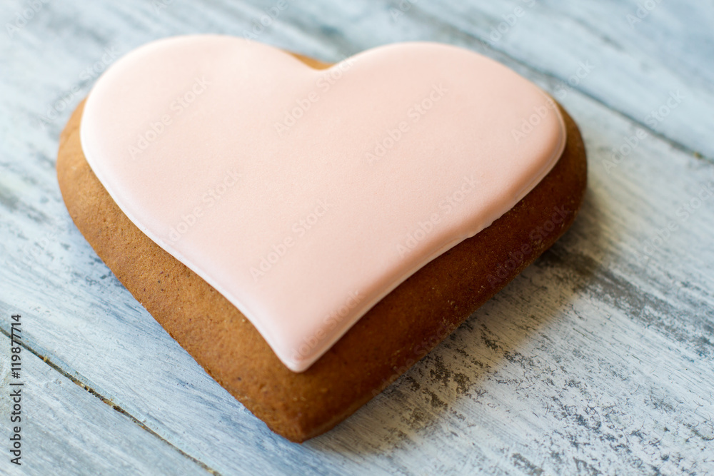 Obraz premium Biscuit shaped as heart. Cookie with light pink glaze. Make surprise for loved one. Recipe for love.