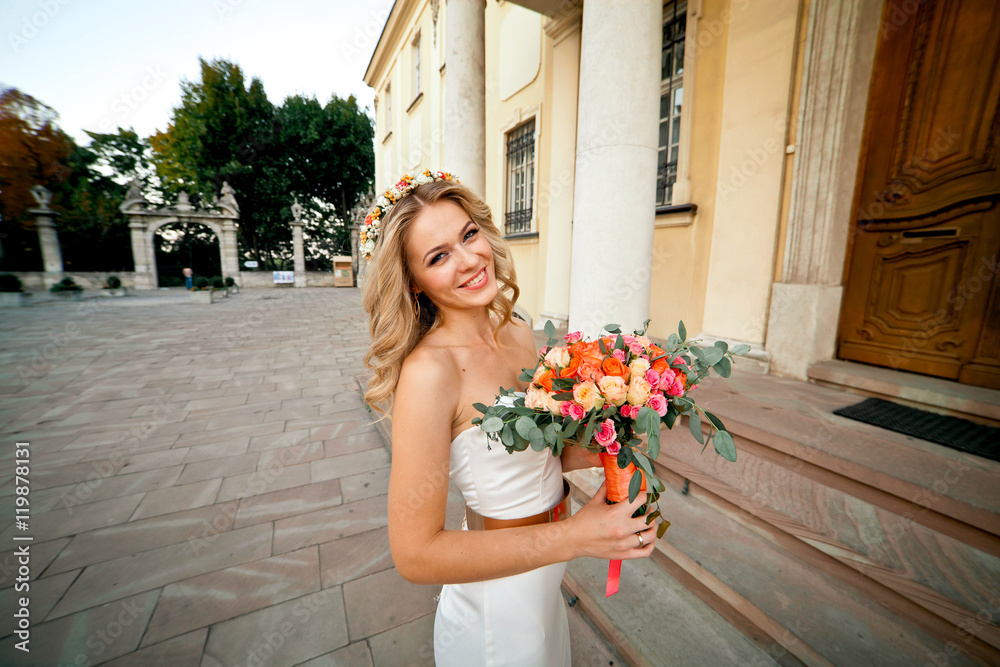 Fototapeta premium Beautiful happy bride is posing with her bouquet