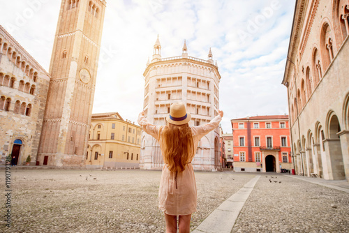 Young female tourist standing back on the central square with cathedral and famous leaning tower on the background in Parma town. Having great vacations in Parma photo