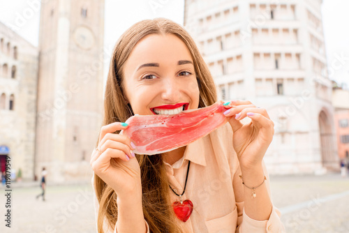 Young woman with prosciutto on the main square in Parma town in Italy. Parma is a city in the north of Italy famous for its prosciutto ham