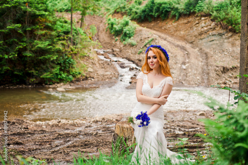 Red haired bride sitting alone near river