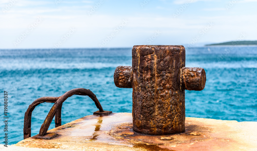 Fototapeta premium Old rusty steel mooring bollard pole on a pier.
