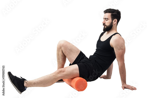 Athlete massaging and stretching legs calf muscles with foam roller. Full body length portrait isolated on white studio background. photo