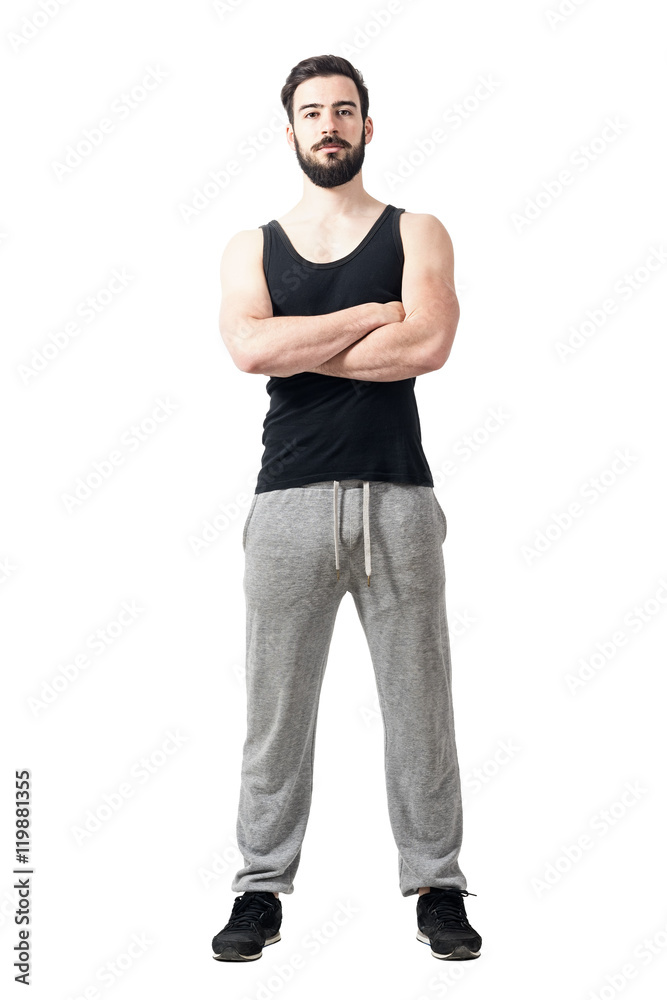 Front view of muscular fitness athlete with crossed arms. Toned desaturated full body length portrait isolated on white studio background. Front view of muscular fitness athlete with crossed arms. Toned desaturated full body length portrait isolated on white studio background.