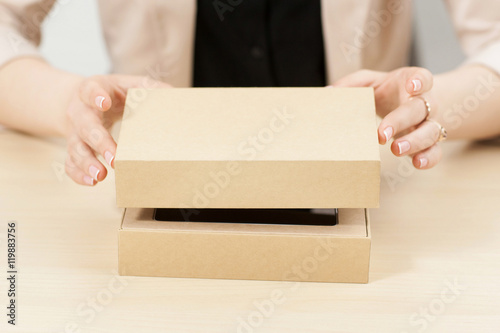 Woman opening box with new parcel, close-up. Female hands lifting lid of yellow carton package. Delivery service. online shopping, gift concept