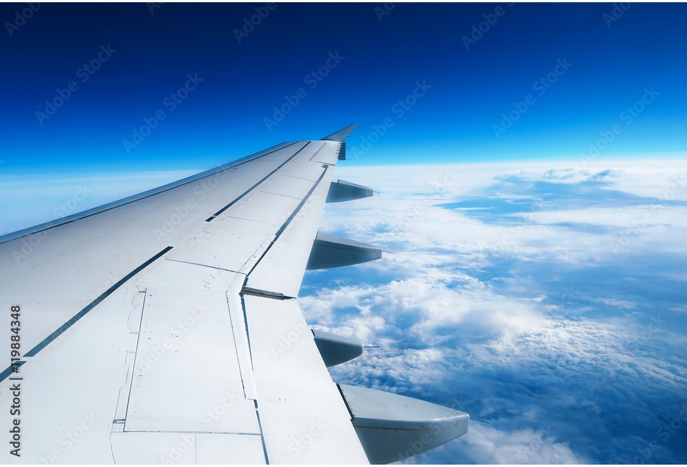 Wing of an airplane flying above the clouds. people looks at the sky from the window of the plane, using air transport to travel.