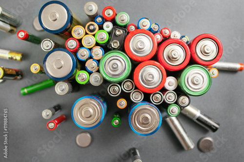 Selection of different batteries, top view on colorful commercial accumulators on gray background. Creative energy composition. Ecology concept
