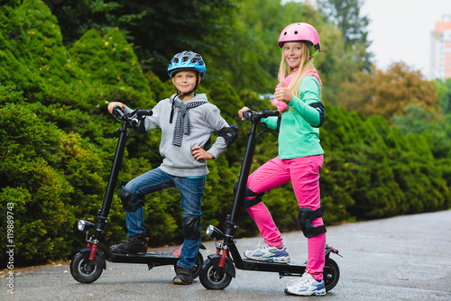 Happy kids standing on electric scooter outdoor