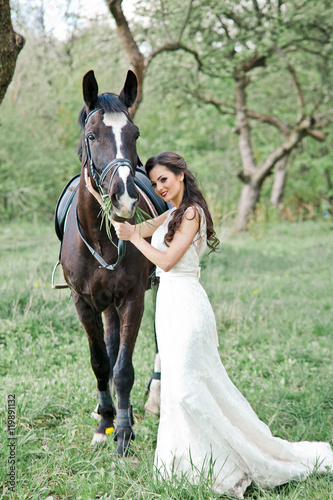 Amazing happy bride is standing with horse