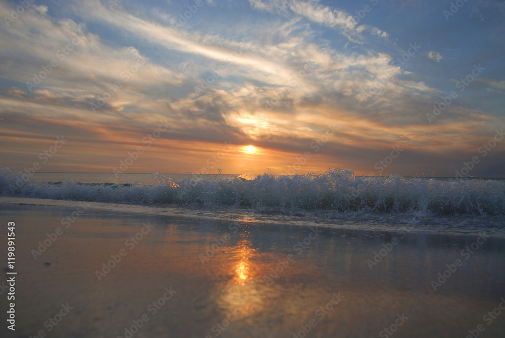 breaking wave on beach at sunset