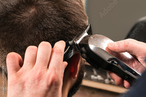 Hairdresser is working with a hair-clipper