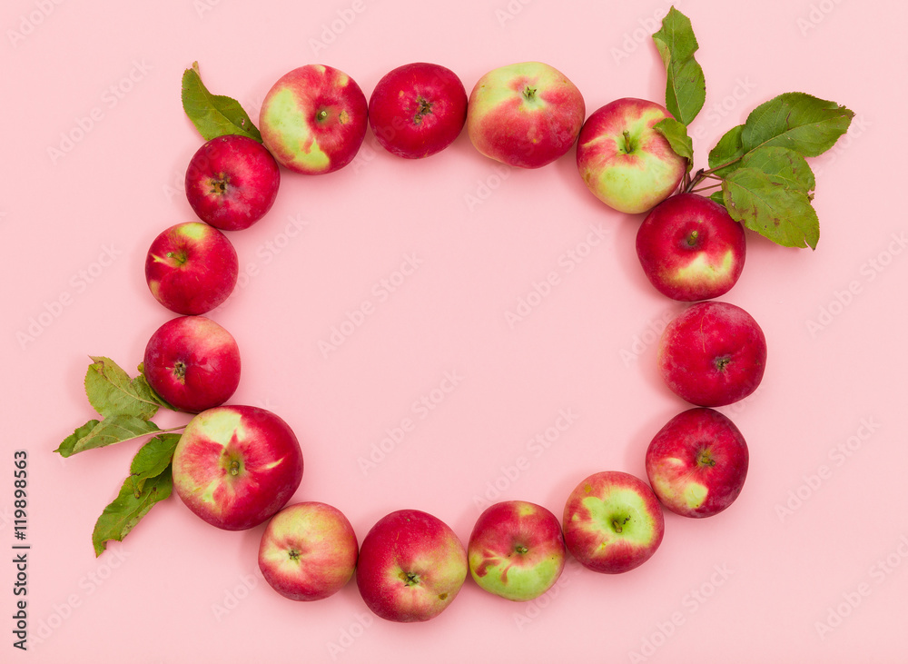 Top view on delicious red organic apples with leaves in a shape of circle on light pink background. Healthy food concept Top view on delicious red organic apples with leaves in a shape of circle on light pink background. Healthy food concept