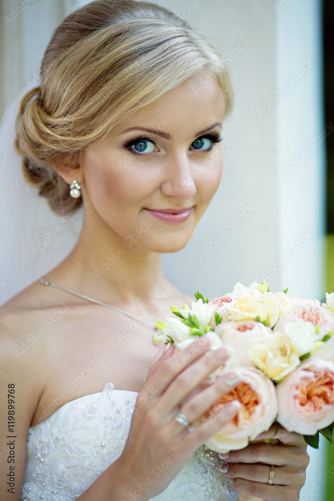 Beauty bride in bridal gown with bouquet and lace veil in the na